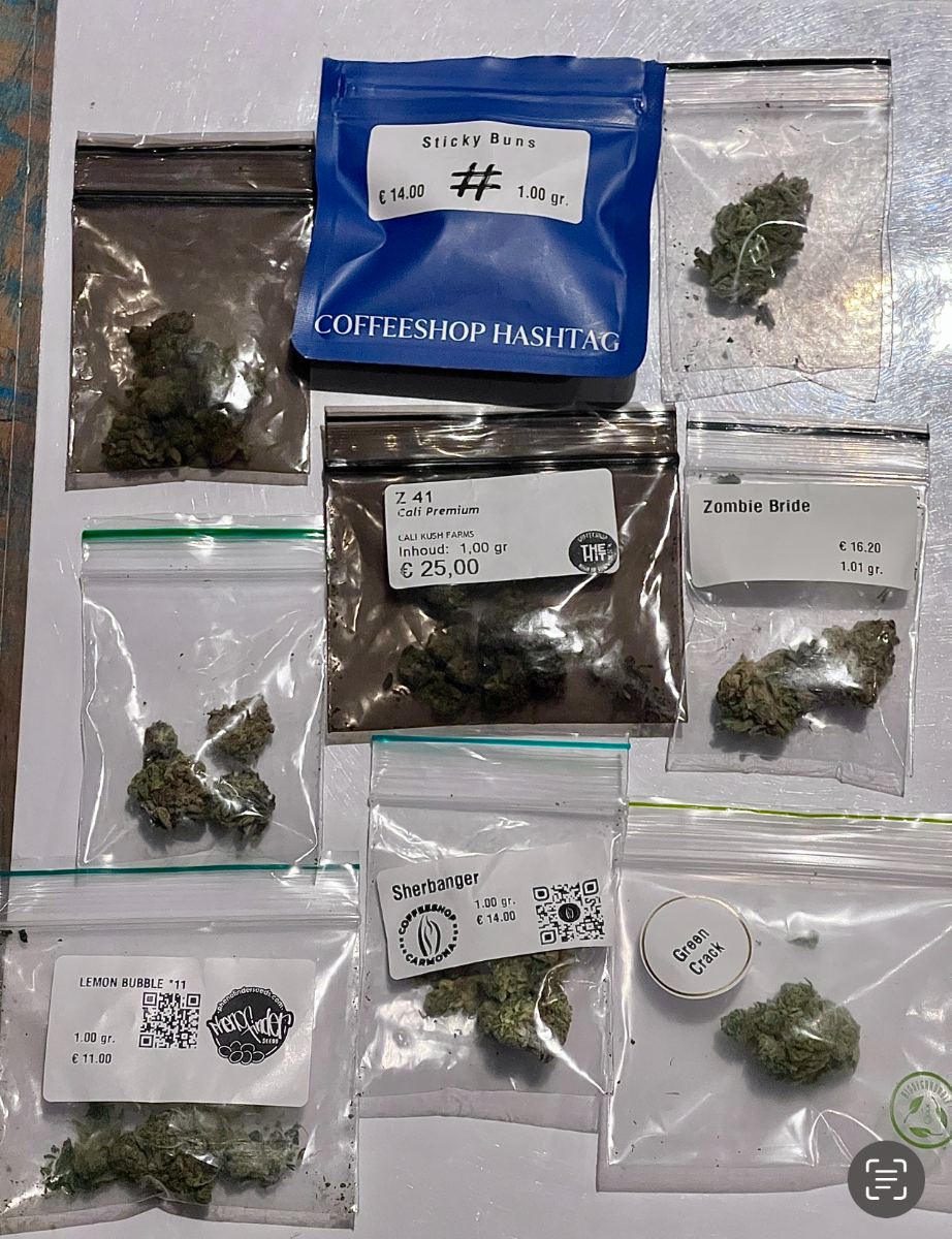 Bags from multiple Amsterdam coffeeshops on a laptop